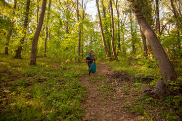 one young man, walking thought forest with bags, tent, and other