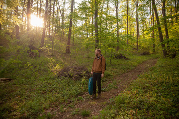 Fototapeta premium one young man, walking in forest, while some camping equipment. smiling and looking at sunlight.