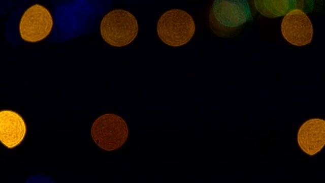 Yellow lights flash along an airport runway at night, marking the boundary between the taxiway and runway. The lights are shown as defocused bokeh.