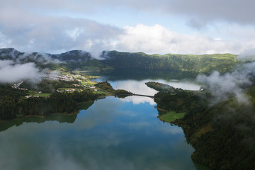Beautiful landscape view of Lagoa Verde and Lagoa Azul on Sao Miguel Island, Azores, Portugal. Reflection on the water and cloudy sky. Thin line of bridge between lakes