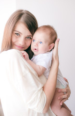 family, child and parenthood concept - happy smiling young mother with little baby at home