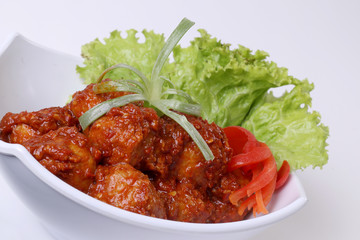 meatballs covered in spicy sauce decorated with tomato lettuce and leeks. on white background