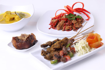 Satay, oxtail, Fish masala curry, and stir fry mushrooms creation Indonesia food on white plate with clean background