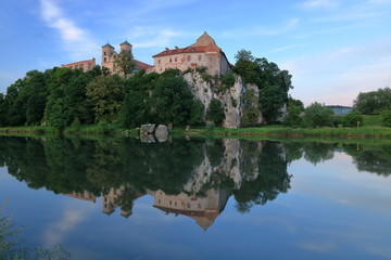 Benedictine abbey building beautifully located at top of rocky hill on Vistula river bank in Tyniec, nearby Krakow, Poland, reflections in water