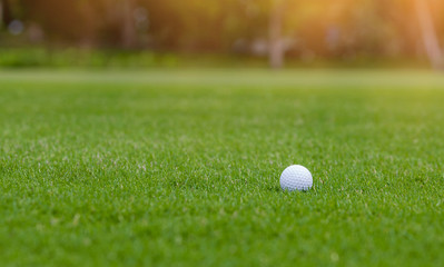 White Golf ball on green course to be shot on blurred beautiful landscape of golf course in bright day time with copy space. Sport, Recreation, Relax in holiday concept	