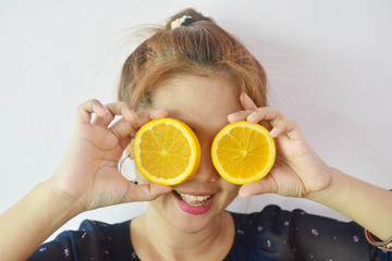 Beautiful young woman holding piece of orange in front of her eye, Healthy lifestyle concept.