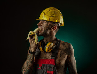 Portrait of a happy smiling miner eating a banana for lunch