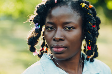 Portrait of a African beauty smiling young black woman in a park with sunlight flare and copy space