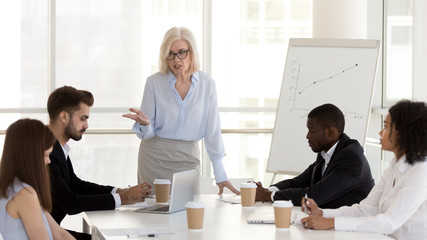 Angry mature businesswoman, boss scold employees for bad work results