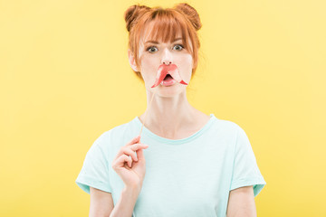 front view of surprised redhead girl in t-shirt holding toy mustache
