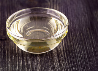 The Cooking vegetable oil in a small glass cup on old wooden table