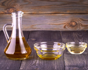 The Cooking vegetable oil in a small glass cup  and jug on old wooden table