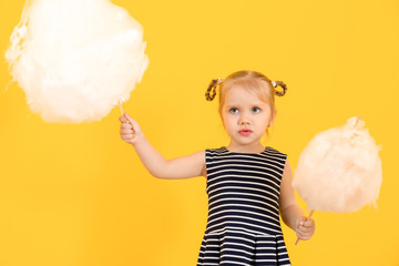 Cute little girl with cotton candy on color background
