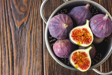 Top view of figs fruits inside metal colander on table.