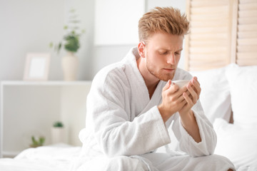 Morning of young man drinking coffee in bedroom