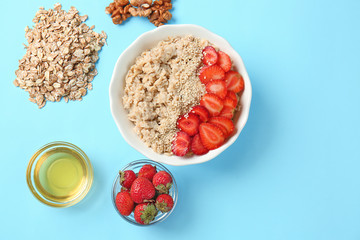 Bowl with tasty sweet oatmeal, strawberry and honey on color background