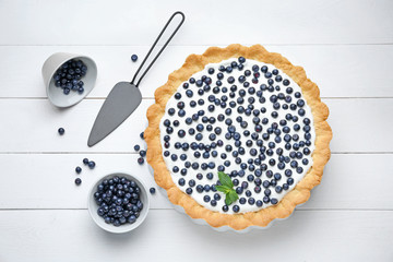 Tasty bilberry pie on white wooden background