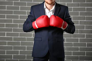 Businessman in boxing gloves against brick wall