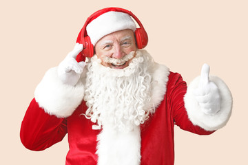 Portrait of Santa Claus listening to music on light background