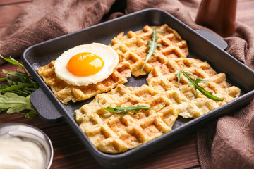 Frying pan with tasty squash waffles and fried egg on table