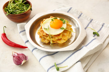 Plate with tasty squash waffles and fried egg on light background