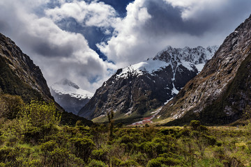 View of Southern Alps in a sunny day on a background of cloudy sky. Road from Milfod Sound to Te Anau, New Zealand.