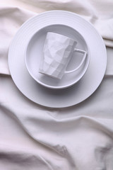 Clean white dishes on white tablecloth