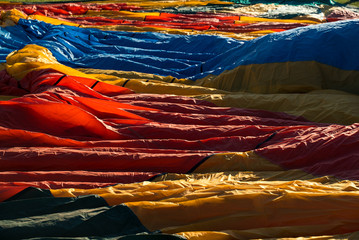 Hot air balloon textiles laying on a green grass. European balloon festival in Spain. International meeting of hot air balloons and flying competition. 