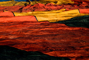 Hot air balloon textiles laying on a green grass. European balloon festival in Spain. International meeting of hot air balloons and flying competition. 