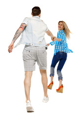 Fototapeta premium Back view of going couple. walking friendly girl and guy holding hands.