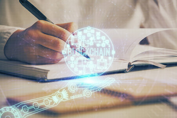 Cryptocurrency hologram over woman's hands writing background. Concept of blockchain. Double...