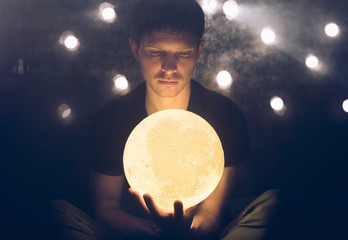 Man holds a yellow moon in his hand 