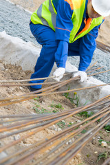 Builder in blue uniform, takes to carry the reinforcement for the Foundation, close-up, with a place for the inscription