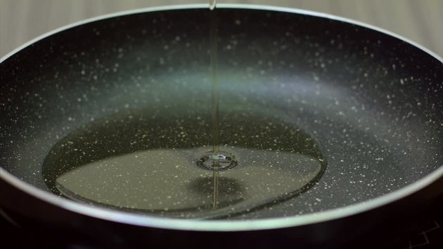 Close up shot of pouring oil into a non stick frying pan. 
