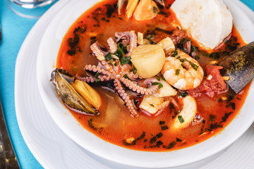 Tomato soup made from chicken, rings of colmar, octopus, mussels and vegetables according to a Mediterranean recipe