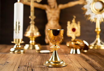 Catholic concept background. The Cross, monstrance and golden chalice on the rustic wooden altar.