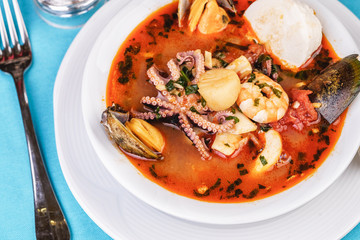 Tomato soup made from chicken, rings of colmar, octopus, mussels and vegetables according to a Mediterranean recipe