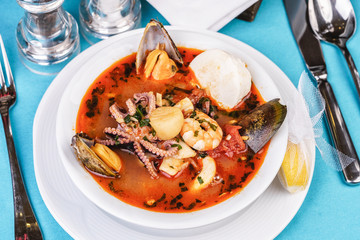 Tomato soup made from chicken, rings of colmar, octopus, mussels and vegetables according to a Mediterranean recipe