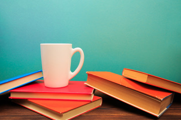  pile of old books with mug , panorma, good copy space  on blue background