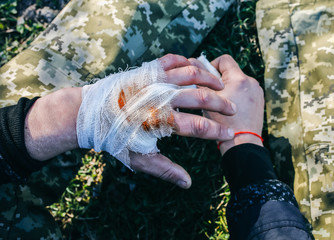 Man is putting bandage on bleeding wound. Injured hand. Cut with a knife. Tourist in the nature....