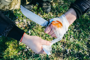 Man is putting bandage on bleeding wound. Injured hand. Cut with a knife. Tourist in the nature....