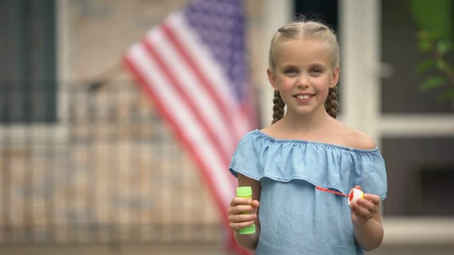 Happy american girl blowing foam bubbles, having fun, happy childhood concept
