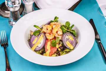Mediterranean salad. grilled prawns, red onion rings, lemon peel, ginger root and vegetables dressed with olive oil
