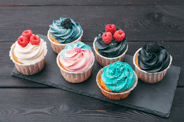 Set of different delicious cupcakes on dark