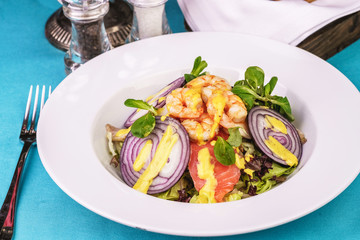 Mediterranean salad. grilled prawns, red onion rings, lemon peel, ginger root and vegetables dressed with olive oil
