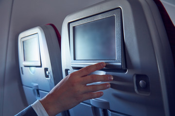 Man using touchscreen in modern airplane seat.