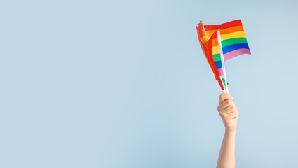 Fototapeta premium Gay flags in women's hand on grey background