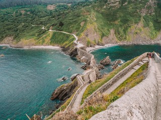 Obraz na płótnie Canvas Picturesque picturesque road winding stairs to the island Gaztelugatxe on the coast of the Bay of Biscay and looks at the mountain. Spain, Basque Country