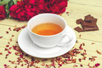 Cup of green tea on table with fresh peony flowers