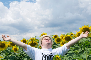 Young man standing with arms wide open in the sunflower field. Happy man with down syndrome in the countryside